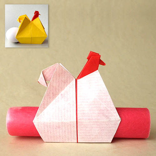 Origami Hen carrying a roll of paper as a message. Designed by Leyla Torres. A rolled